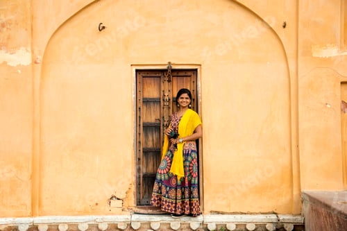 Preview: Woman tourist in front of old door at Amber fort, Jaipur, India