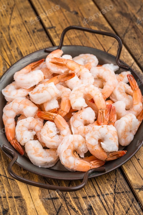 Preview: Frozen pink prawns in serving pan with rosemary on wooden table. Preserved seafood ingredient
