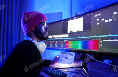 Preview: Creative individual editing video content in a dimly lit studio workspace at night