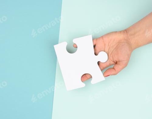 Preview: Female hand holds a fragment of a white large puzzle on a blue background
