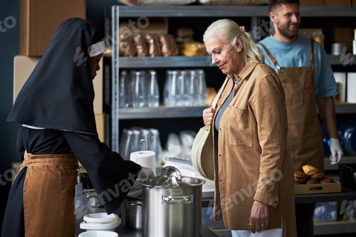 Preview: Portrait of Senior Woman Interacting with Nun in Kitchen