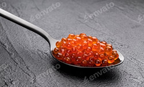 Preview: Red caviar in spoon close-up on black stone background