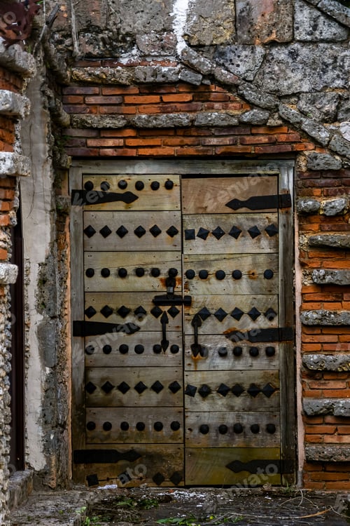 Preview: Vertical shot of an old wooden door with metal inserts of the Altos de Chavon, Dominican republic