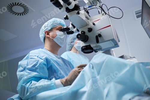 Preview: Male Surgeon Performing Operation Using Surgical Microscope