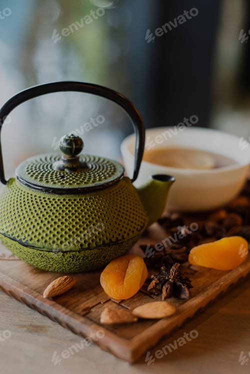 Preview: Close-up shot of a vintage green teapot and dry fruits and a tea with lemon in a cup
