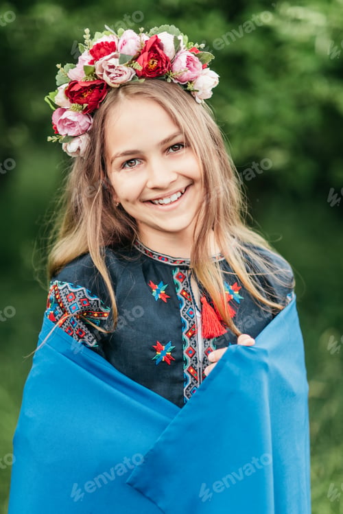 Preview: Ukrainian child girl in embroidered shirt vyshyvanka with yellow and blue flag of Ukraine in field.