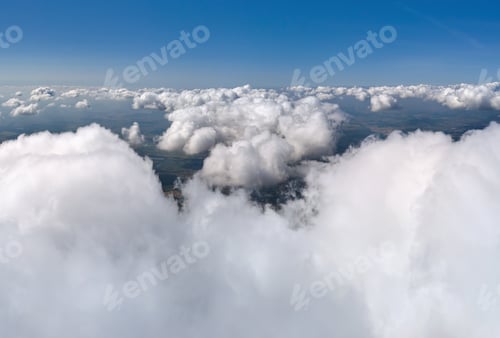 Preview: Aerial view from airplane window at high altitude of earth covered with puffy cumulus clouds