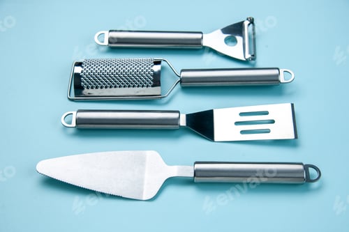 Preview: Front view of stainless kitchen tools lying side by side on soft blue wave background with free