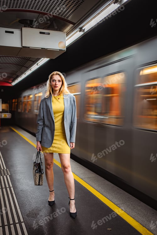 Preview: Woman standing on subway platform with passing train