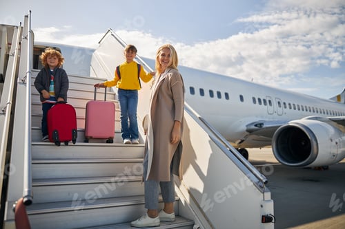 Preview: Pleased mom with her children boarding the plane