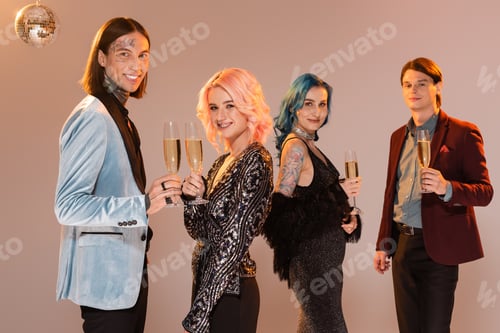 Preview: cheerful queer people in festive and elegant clothes holding champagne while celebrating christmas