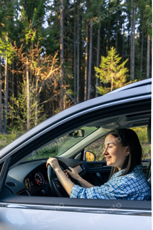Preview: Woman driving in a car in the forest, mountain travel concept.