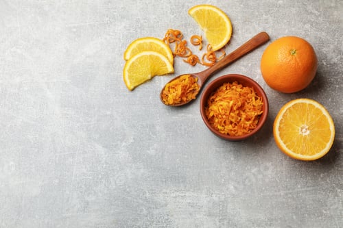 Preview: Orange zest and fresh fruits on light grey table, flat lay. Space for text