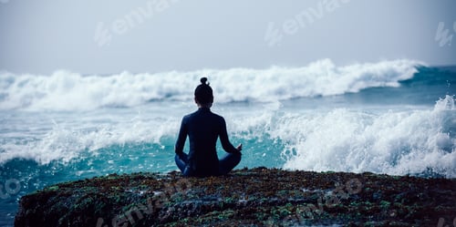 Preview: Woman meditation at the seaside cliff edge facing the coming strong sea waves
