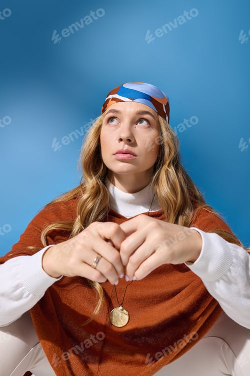Preview: A young beautiful plus size woman in a vibrant scarf poses thoughtfully against a blue background