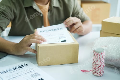 Preview: Young entrepreneur packing online order product for shipping.