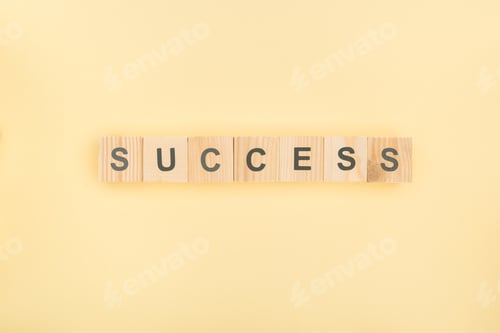 Preview: top view of success lettering made of wooden cubes on yellow background