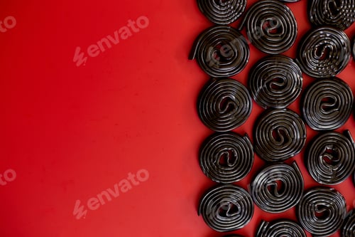 Preview: Flat lay tasty black liquorice candies on red background