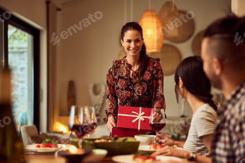 Preview: A smiling woman opens a gift during the birthday dinner.