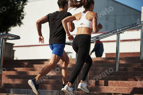 Preview: On the stairs. Man and woman have fitness day and running in the city at daytime