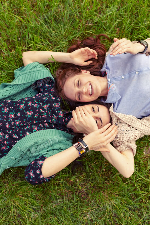Preview: Top view of smiling friends lying on grass having fun