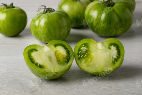 Preview: Whole and halved fresh green zebra tomato close up