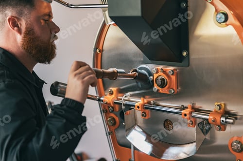 Preview: Close up of business owner operating modern coffee bean roasting machine