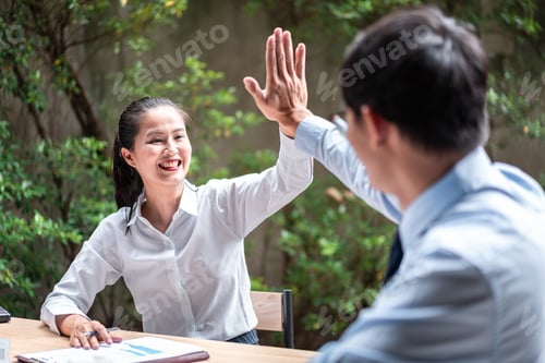 Preview: Young business woman and businessman giving hand high five after job well done