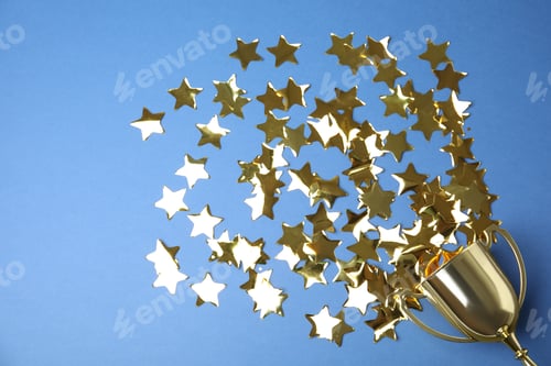 Preview: Gold trophy cup and confetti on blue background, flat lay. Space for text