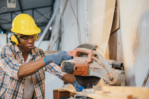 Preview: Construction worker in a yellow helmet using a chop saw to cut wood, with a vacuum cleaner