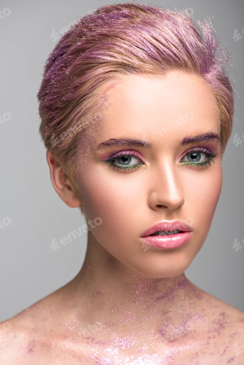 Preview: attractive woman with violet glitter on face and hair looking at camera isolated on grey