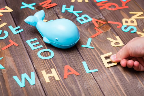 Preview: Children's hands make up the word "whale" from colored carved cardboard letters and a toy whale