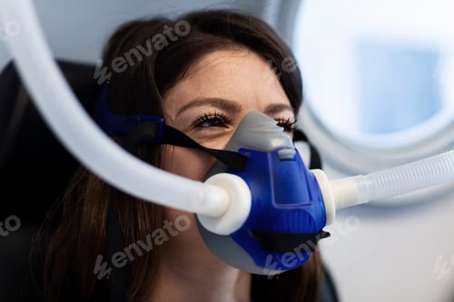 Vista previa: Woman breathing through oxygen mask in hyperbaric chamber.