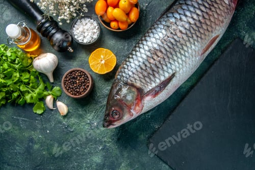 Preview: top view fresh raw fish with kumquats and greens on dark background food health water fish color
