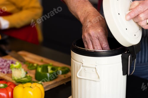 Preview: Midsection of caucasian senior man preparing food, composting vegetable waste in kitchen