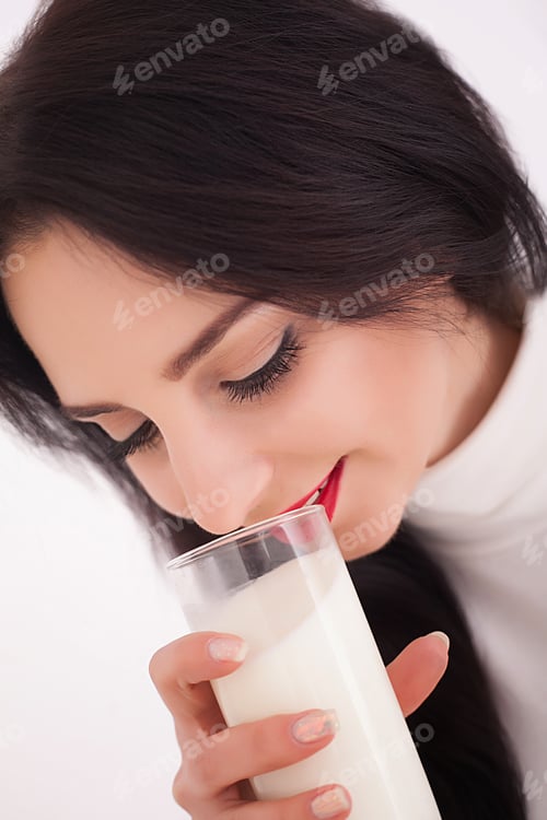 Preview: Cute healthy woman is drinking milk from a glass isolated on white background.