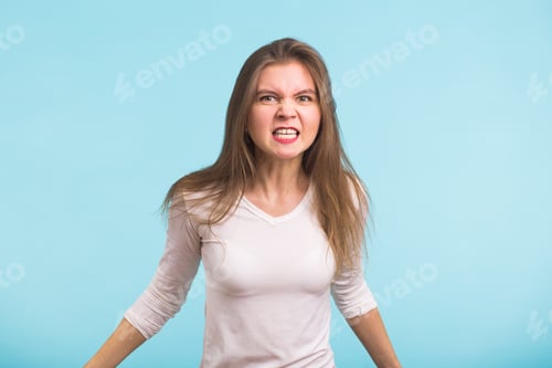 Preview: Angry aggressive woman with ferocious expression on blue background