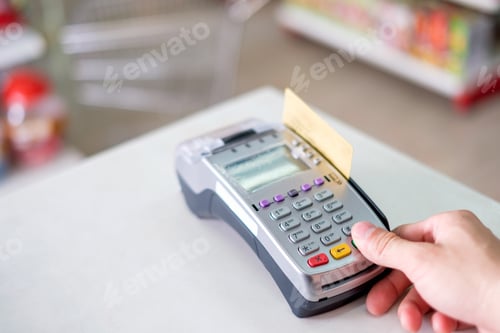 Preview: Hand press with swiping credit card on payment terminal in store