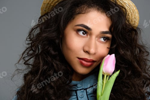 Preview: close-up portrait of beautiful young woman with tulip flower isolated on grey