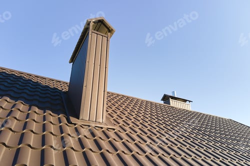 Preview: Chimney on house roof top covered with metallic shingles under construction.