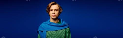 Preview: Young man showcases modern fashion trends in a vibrant blue setting with style and confidence