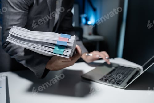 Preview: Employee checking important details of document on laptop, Documents were stacked on the desk, A bus