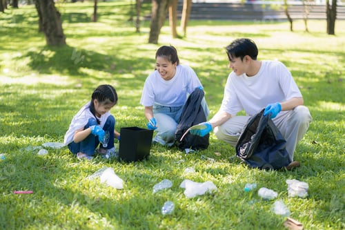 Preview: Happy Asian family collecting plastic bottles at the park.