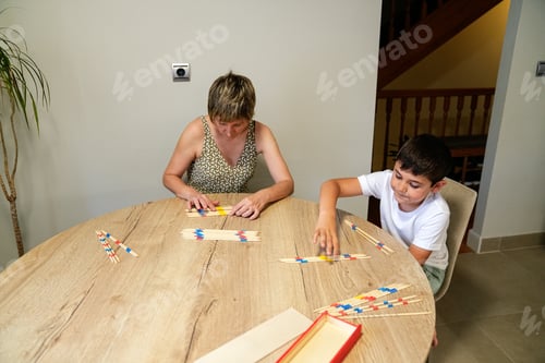 Preview: Mother and son concentrating while arranging sticks in a table game.