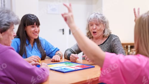 Preview: Seniors and caregiver playing board game in nursing home