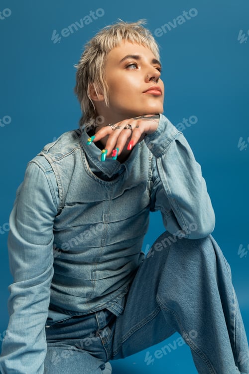 Preview: Stylish young woman poses confidently against a vivid blue backdrop with creative flair