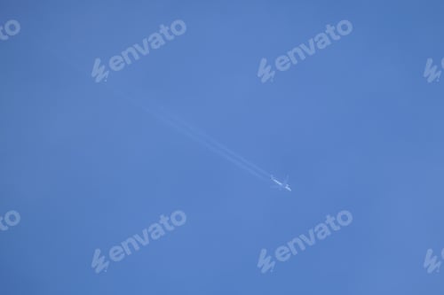Preview: Distant passenger jet plane flying on high altitude on clear blue sky leaving white smoke