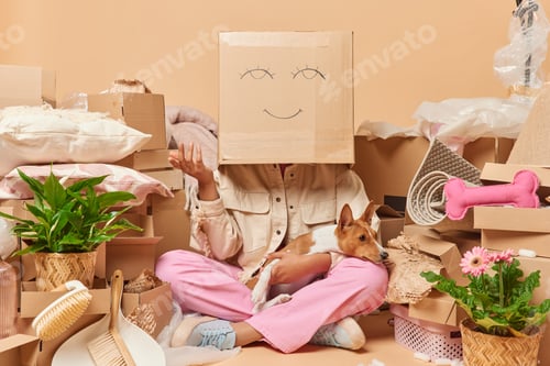 Preview: Faceless woman poses with carton box on head foolishes around draws face while packing things in pac