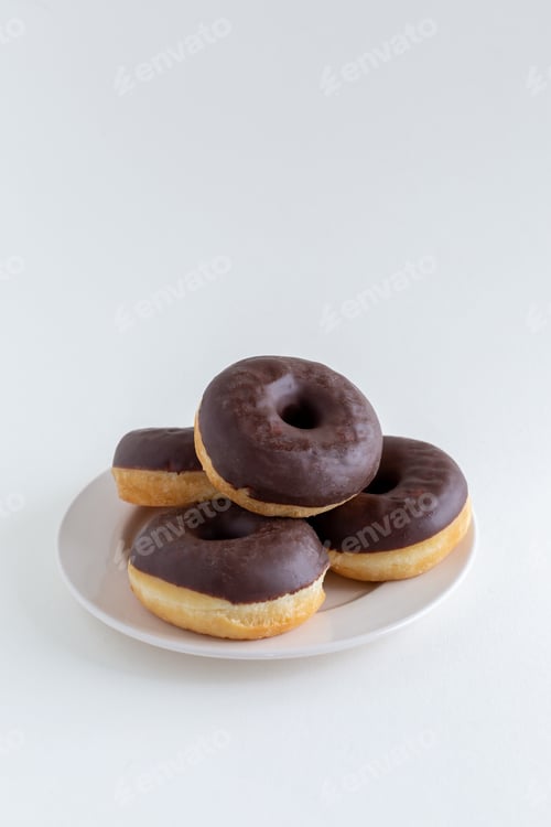 Preview: A group of chocolate donuts on a white plate, white background, with copy space
