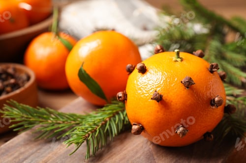 Preview: Delicious fresh tangerines with cloves on wooden table, closeup. Christmas celebration